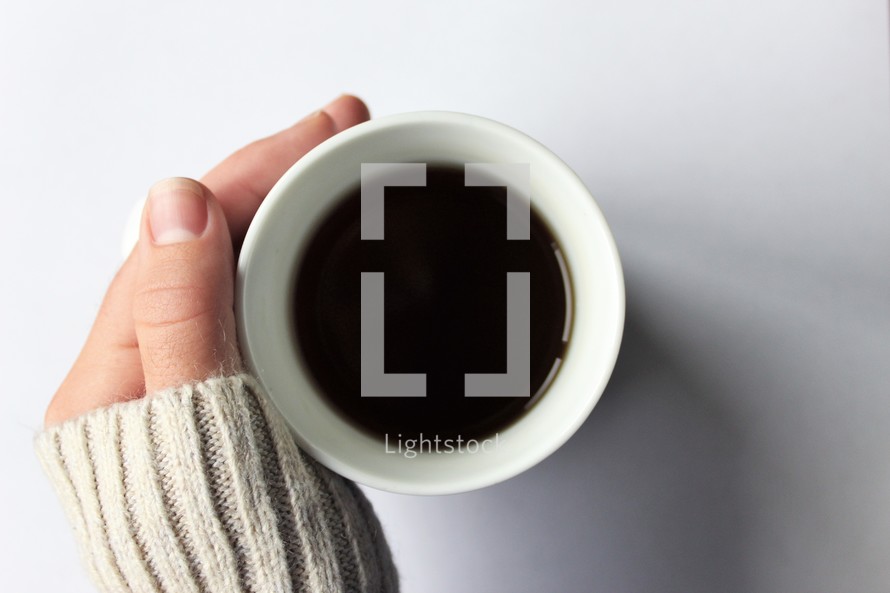 hand in a sweater on a coffee cup 