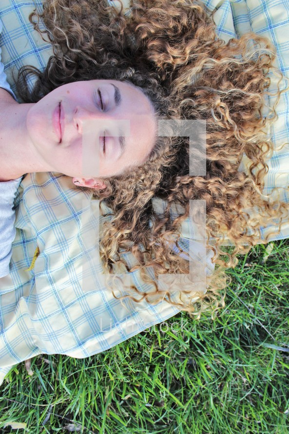 a woman napping on a blanket in the grass