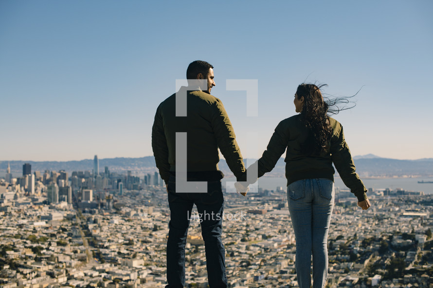 a couple holding hands and view of a city 