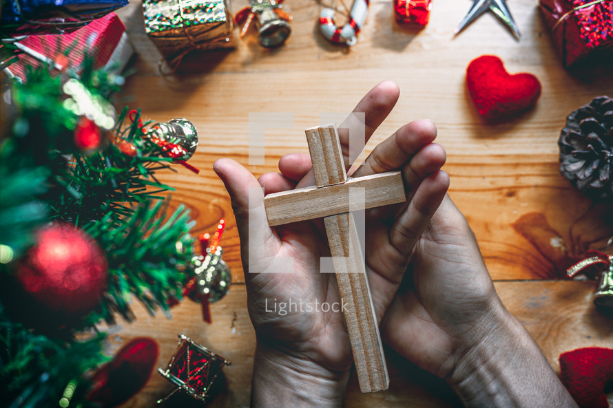 hands holding a cross, praying at Christmas 