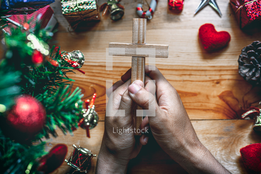 praying hands holding a cross at Christmas 