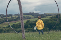 a boy in a rain jacket standing in a field 