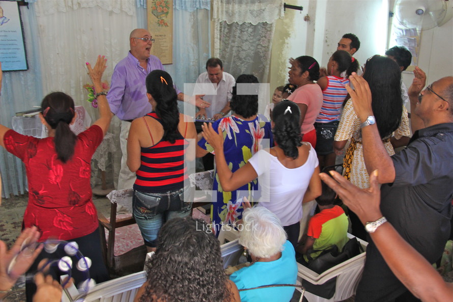 Hands raised in praise at a worship service in a small church in Havana, Cuba