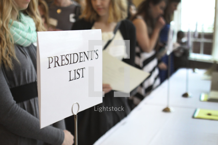 president's list - young women standing in line checking in to a conference 