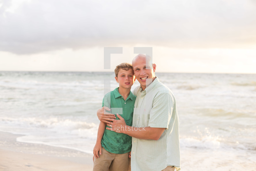 father and son hugging on a beach 