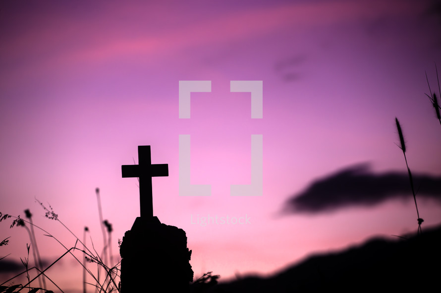a silhouette of a cross against a purple sky 