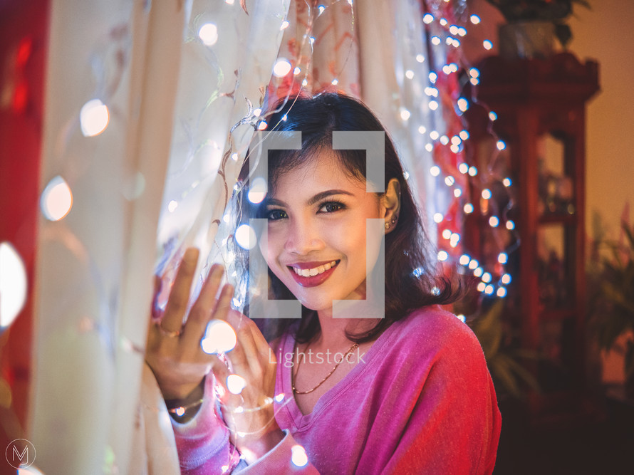 a woman holding a string of fairy lights 