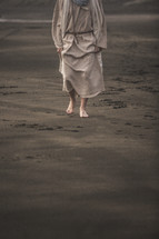 Jesus walking barefoot on a beach 