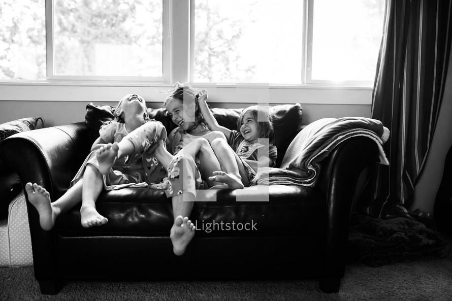 sisters laughing on a couch 