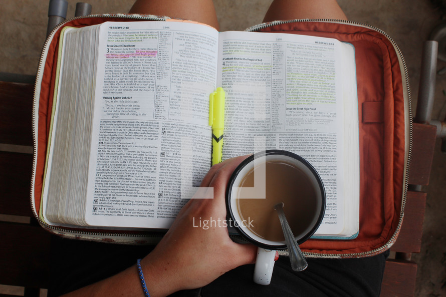 open Bible in a lap and mug 