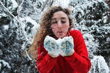 woman blowing snow out of mittens 