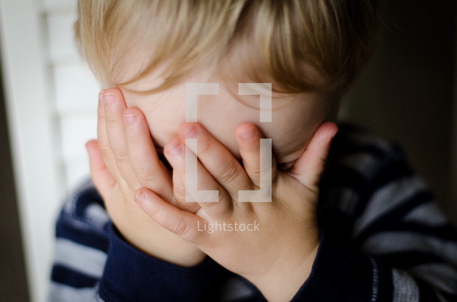 a toddler boy playing peek-a-boo