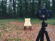 a camera on a stand pointing to a chair outdoors 