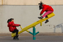 two little girls on a seesaw 