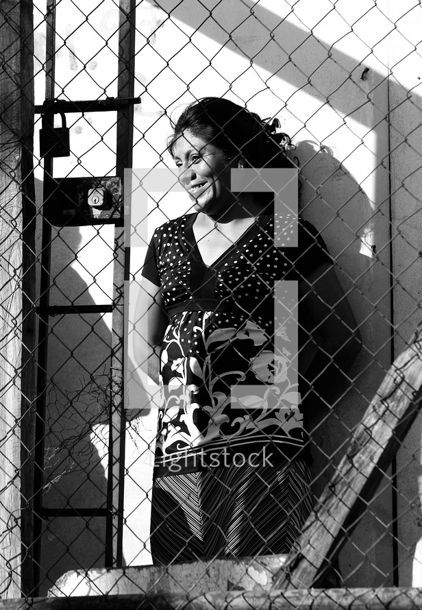 Woman standing behind locked fence
