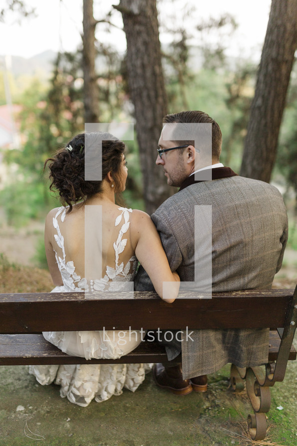 bride and groom sitting on benches outdoors 