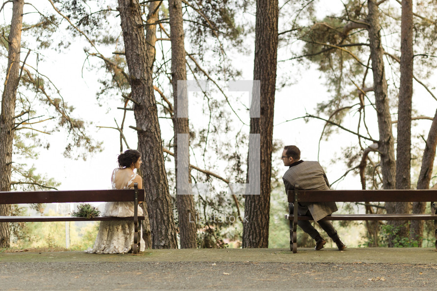 bride and groom sitting apart on benches 