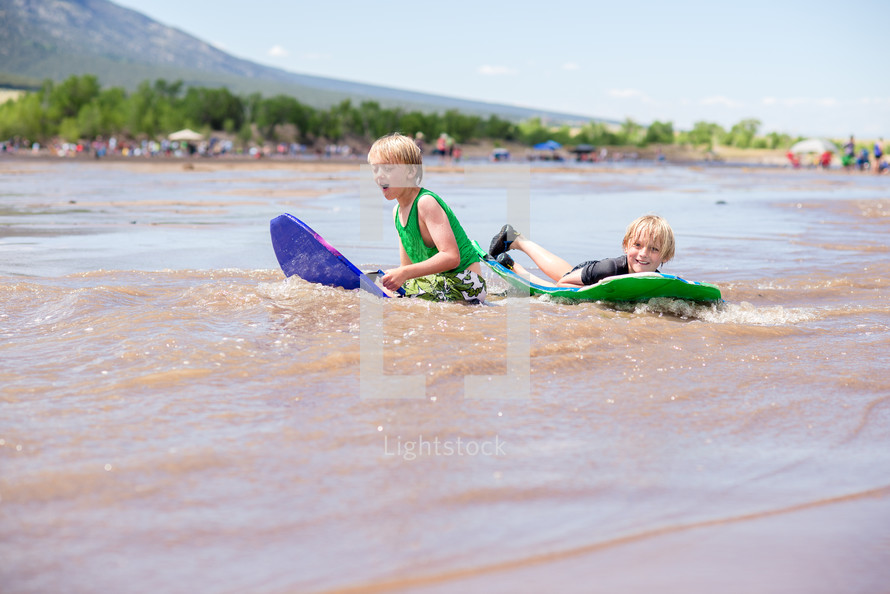 boys skim boarding on a beach 