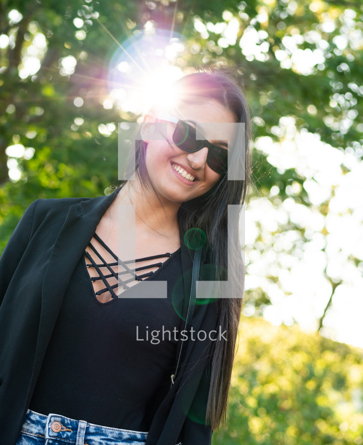 Woman in black shirt and jean skirt with sunlight and bokeh