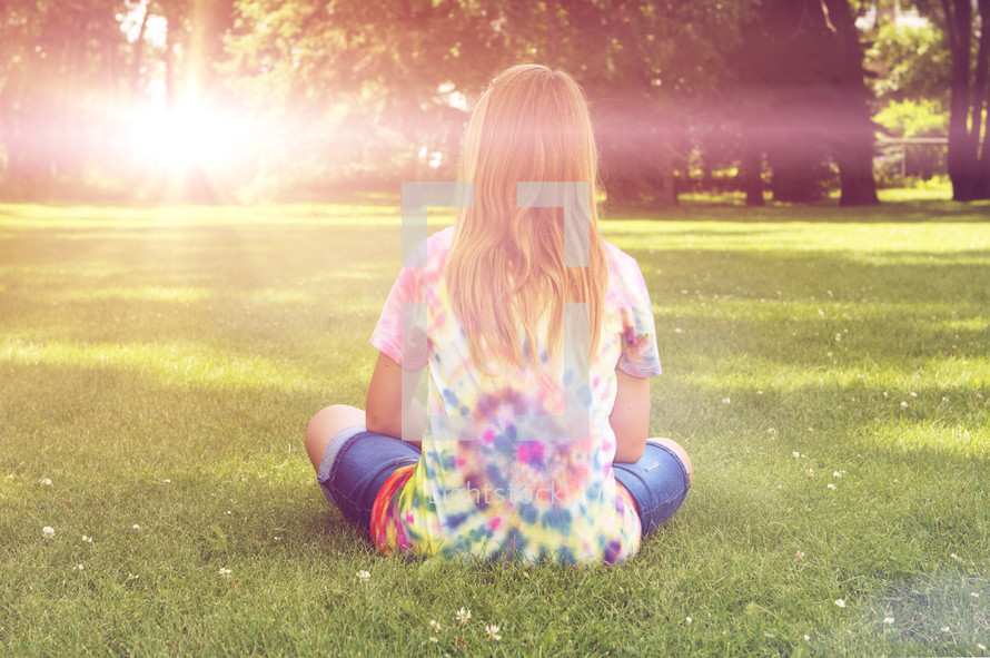young girl sitting in the park on a sunny summer day
