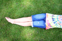young girl with legs crossed laying in the park on a sunny day