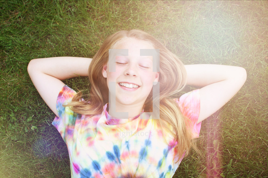 happy smiling young girl lying in the grass