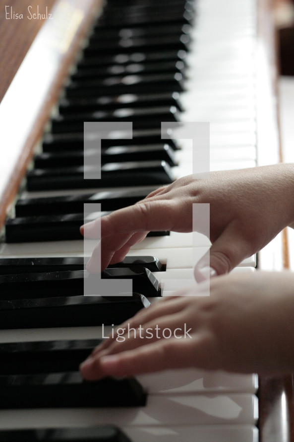A child's hands playing a piano.