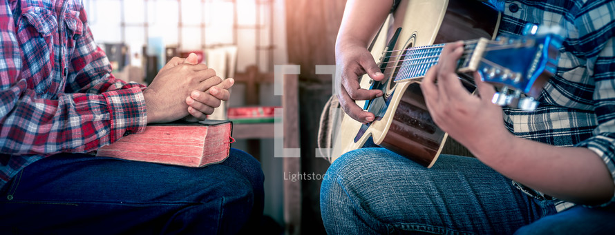 hands of young christians share a bible and sing with a guitar to worship God, Christian worship
