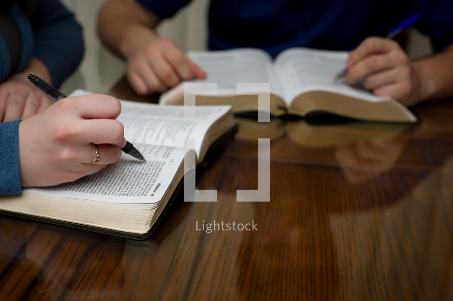 two men at a Bible study with their pens on a Bible