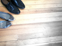 men's and women's dress shoes on a wood floor 