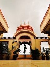 A silhouette of a woman standing in an ornate archway
