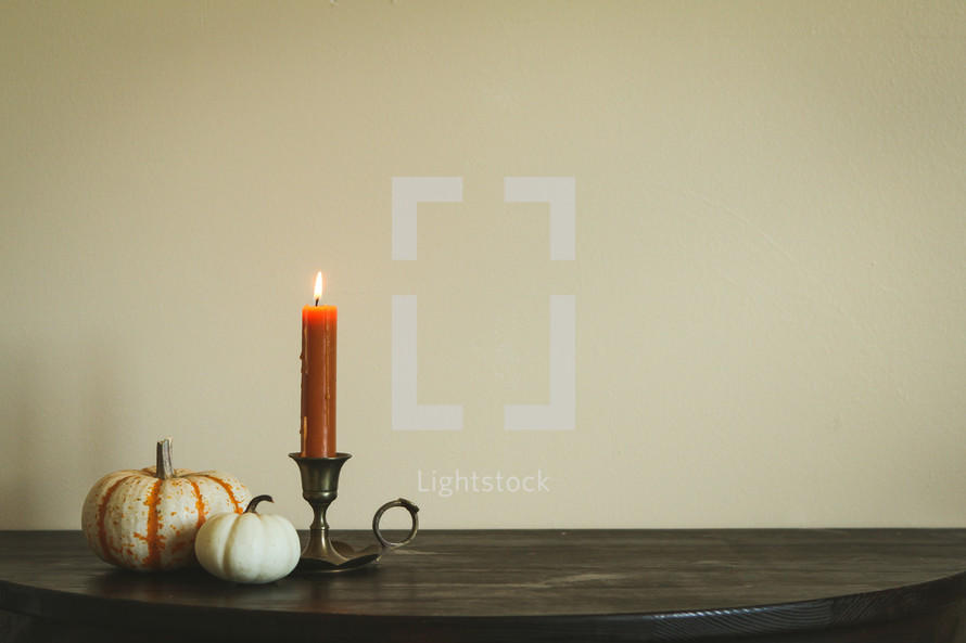 pumpkins and candlestick on a wood table