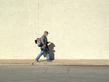 A homeless man walking down a sidewalk. 