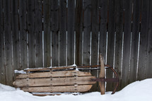 a sled against a wooden fence 