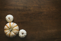 three pumpkins in a corner on a wood table
