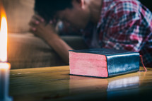 man praying near a Bible 