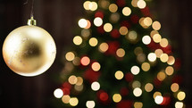 Gold ball decoration with blurred Christmas tree