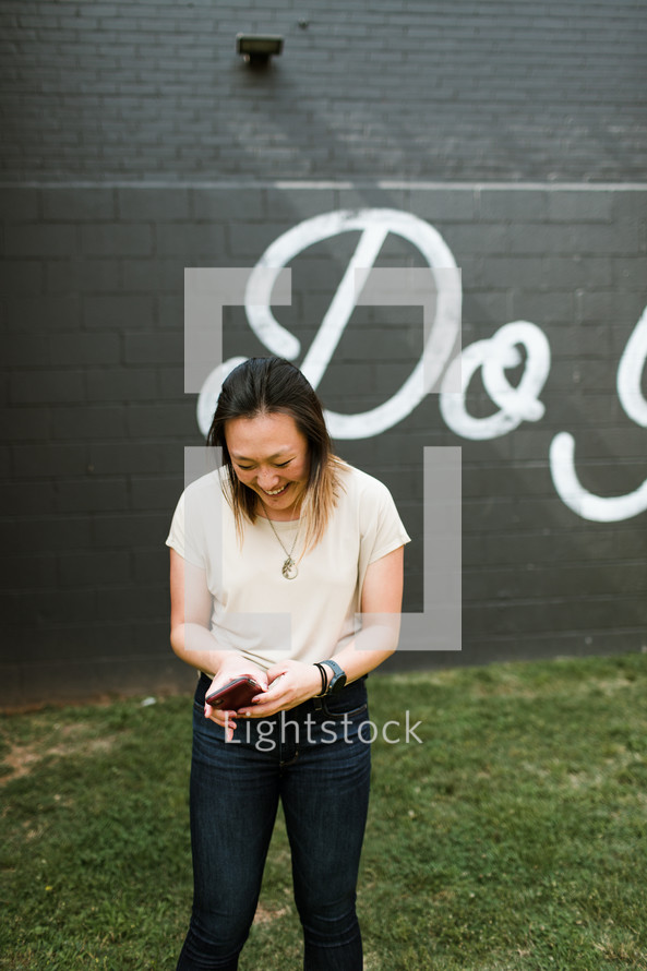 a smiling young woman standing in front of a do good sign 