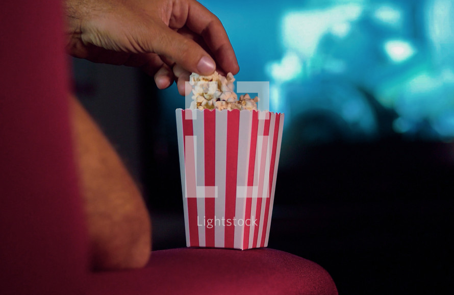 a man eating popcorn watching movies 
