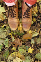 woman's boots standing in fall leaves 