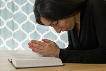 a woman praying over the pages of a Bible 