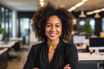 A Black woman with curly hair smiling confidently in an office