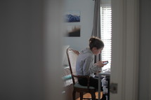 teen girl sitting at a desk texting in her room 