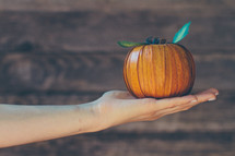 hand holding a woven pumpkin 
