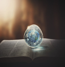 earth paperweight on the pages of a Bible