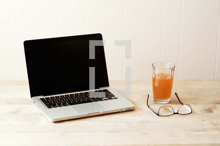 laptop computer and drinking glass on a desk 