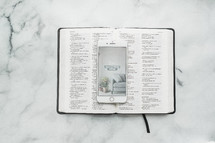 overhead view, smartphone, opened Bible, and notebook on a table