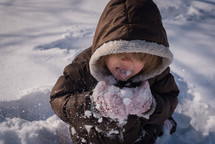 a toddler eating snow 