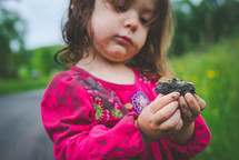 a girl picking up rocks in dirt 
