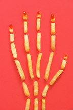 Human Hand Concept With French Fries on Red Background